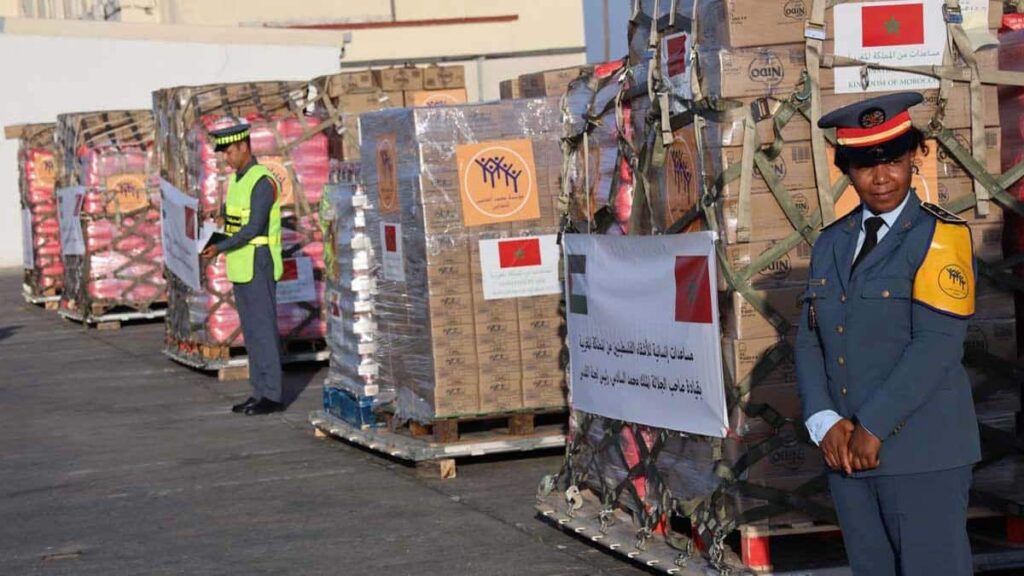 Des membres des Forces Armées Royales encadrent des palettes de cartons d’aide humanitaire portant le drapeau marocain, prêtes à être acheminées vers Gaza.