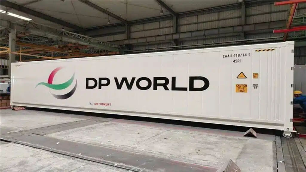Conteneur réfrigéré blanc de DP World sur une plateforme industrielle, avec le logo de l’entreprise et des marquages de série.